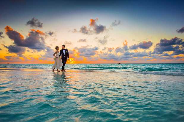 Wedding photoshoot of bridegroom and bride at sunset by the sea
